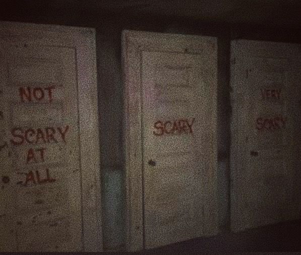 three doors that have been vandalized with red spray paint and not scary at all written on them