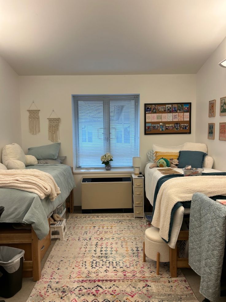 a bedroom with two beds and a rug on the floor in front of a window