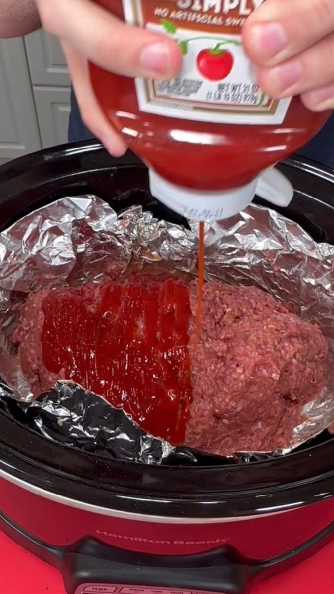 someone is pouring ketchup on top of a meatloaf in an air fryer