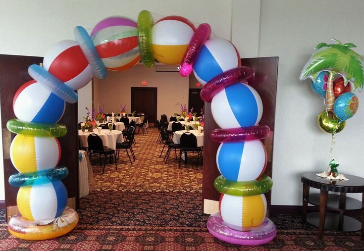 an arch made out of balloons and other decorations in a banquet hall with tables set up for formal function