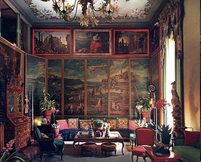 a living room filled with lots of furniture and paintings on the wall above it's windows