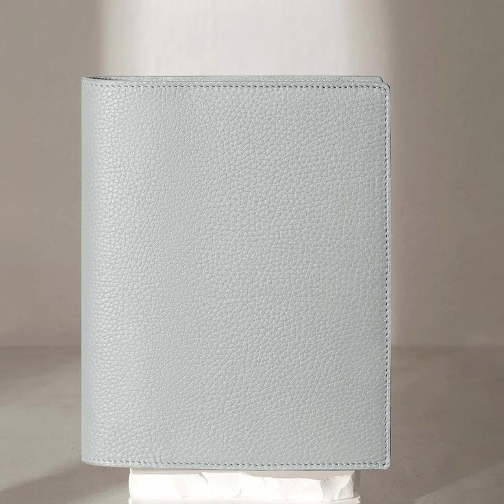 a white leather wallet sitting on top of a tissue dispenser