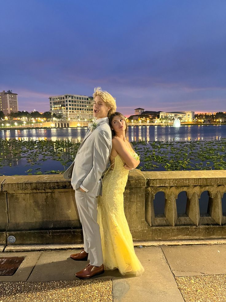 a man and woman standing next to each other in front of a body of water