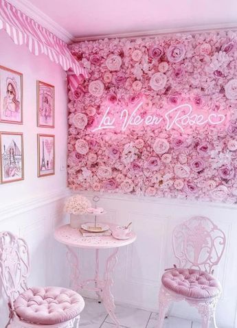 two chairs and a table in a room with pink flowers on the wall behind them