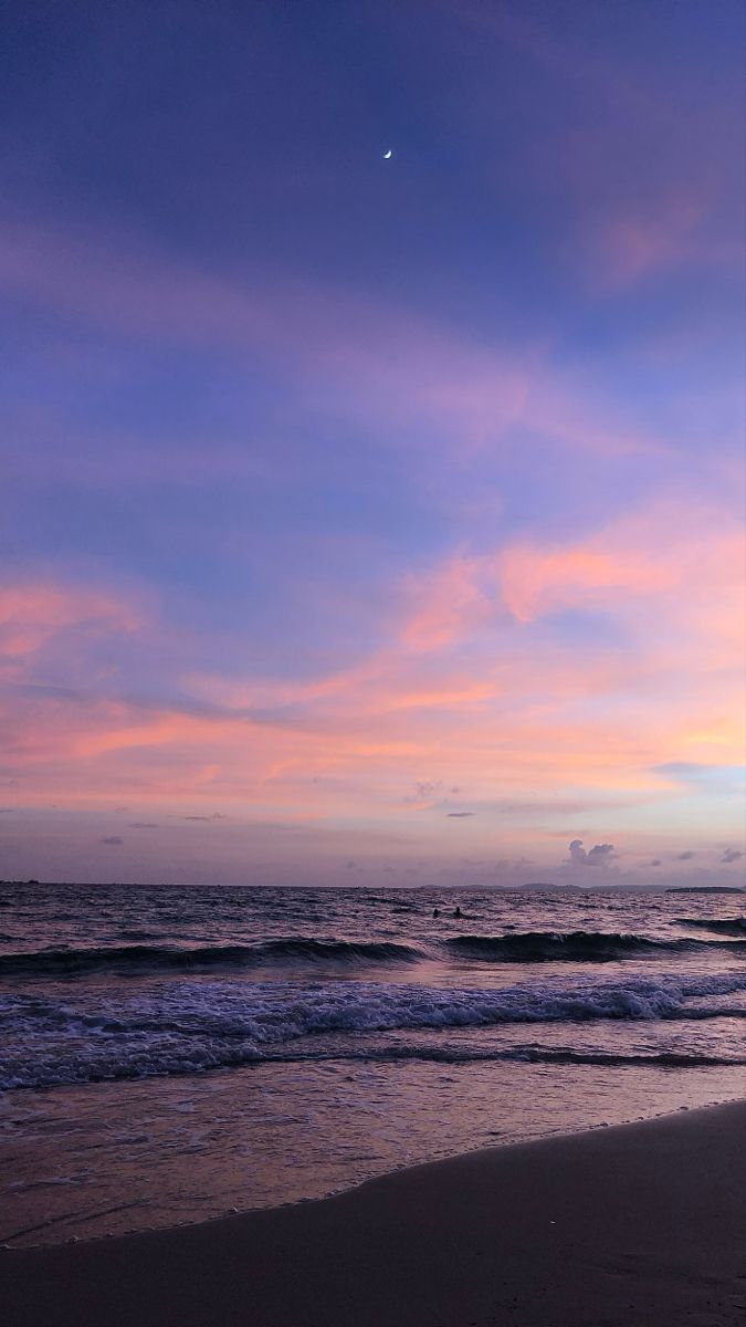 the sun is setting over the ocean with waves coming in