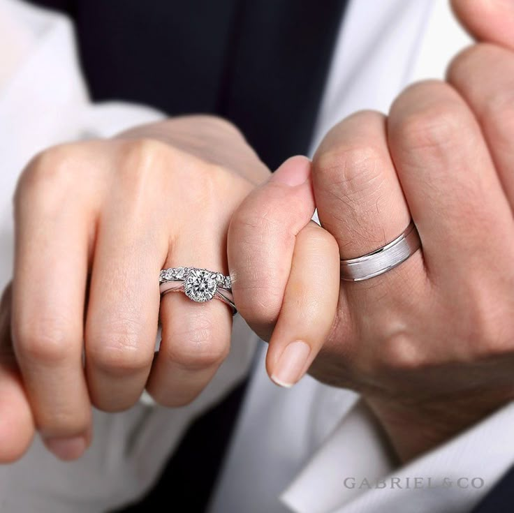 a man and woman holding hands while wearing wedding rings