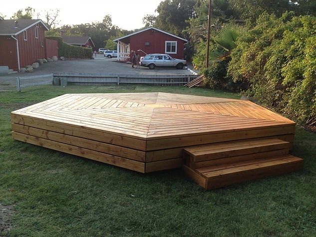 a wooden deck in the middle of a yard with steps leading up to it's top