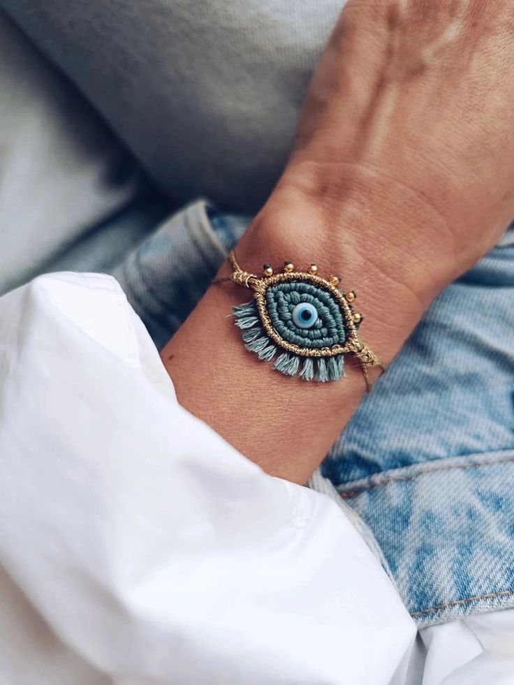 a woman wearing a bracelet with an evil eye on it's wrist and holding onto her arm