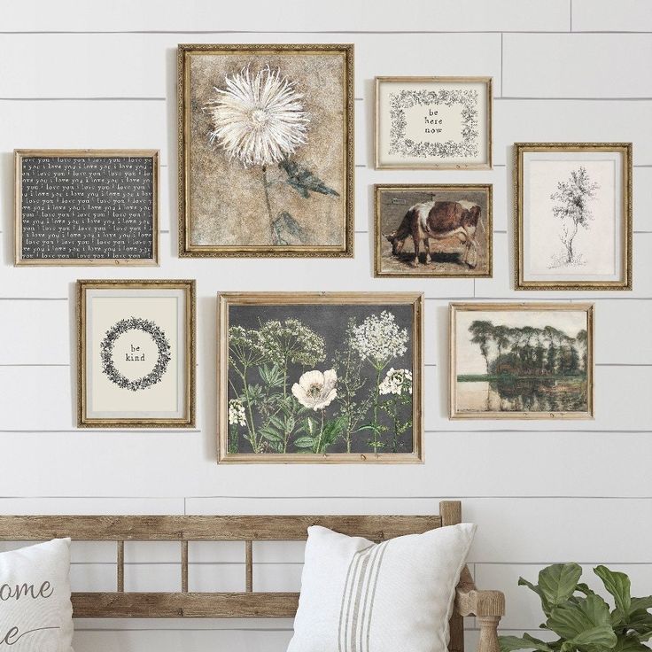 a bench in front of a wall with many framed pictures and flowers on the wall