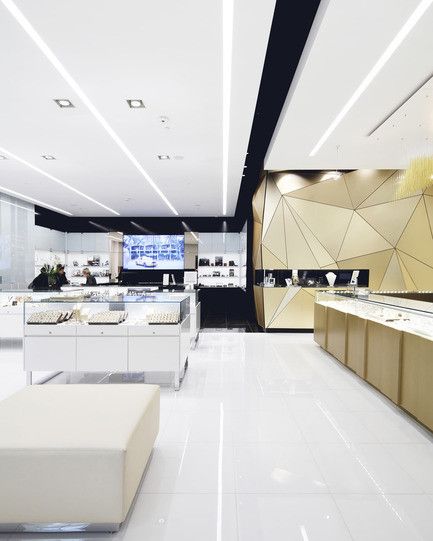 the interior of a jewelry store with white and gold accents on the walls, counter tops, and benches