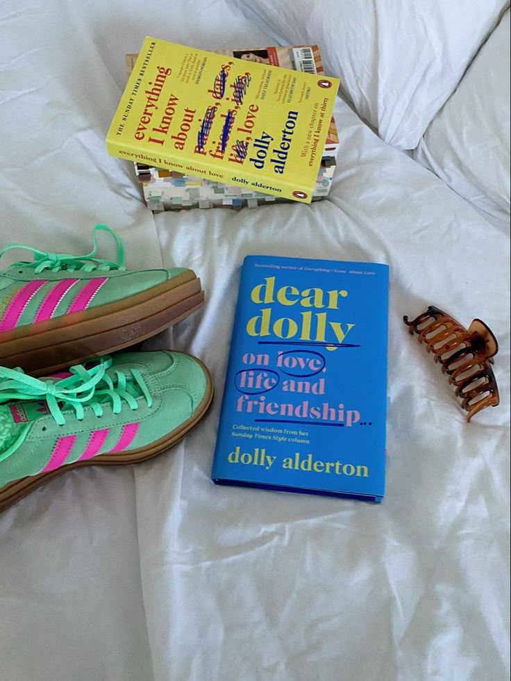 a pair of tennis shoes sitting on top of a bed next to a paperback book