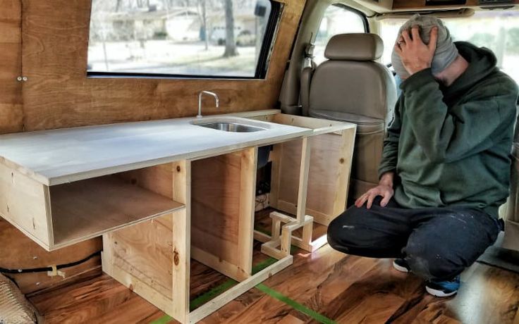 a man sitting in the back of a van talking on a cell phone next to a sink