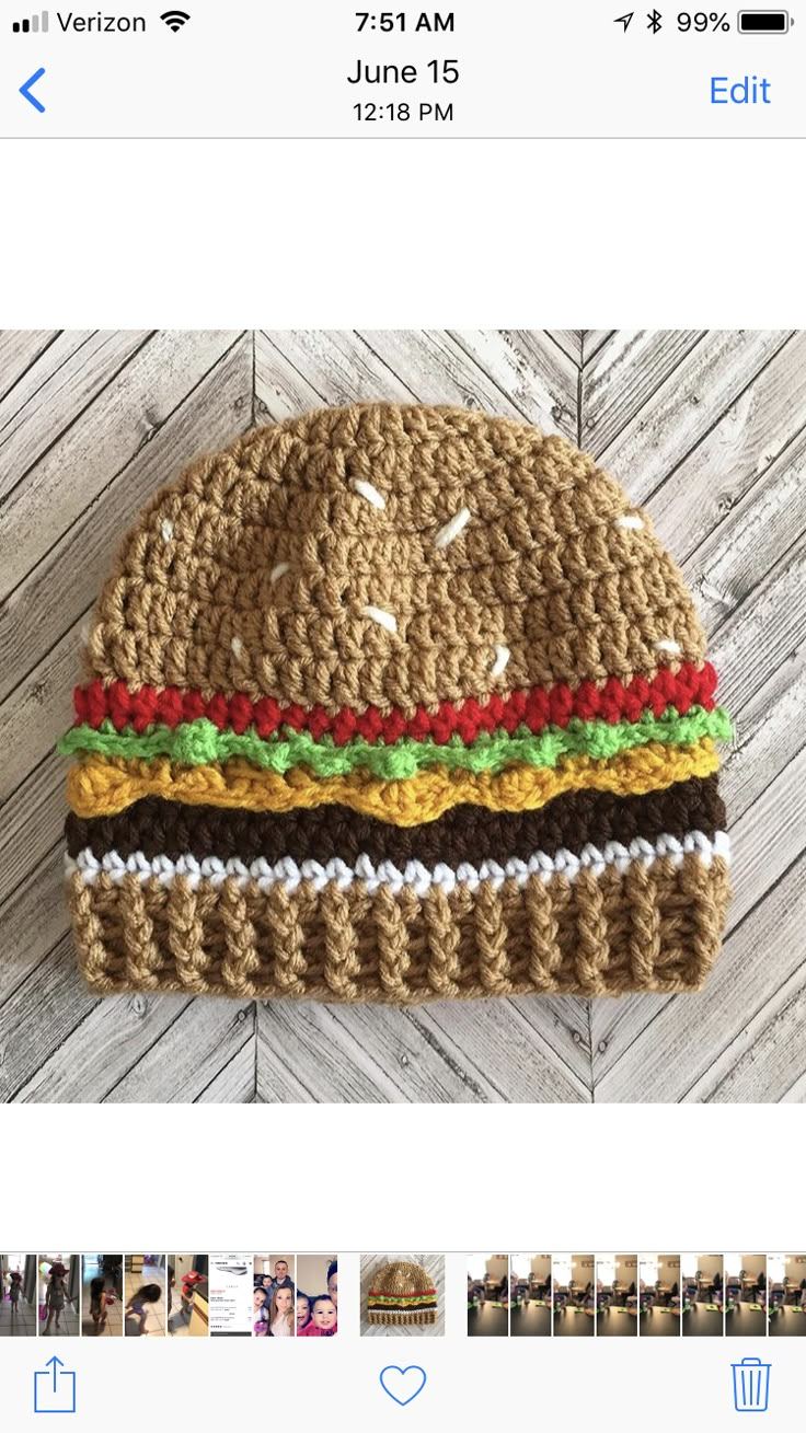 a crocheted hat with a hamburger on the front and bottom, sitting on top of a wooden floor