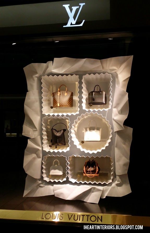 an assortment of purses and handbags displayed in a display case on a wall