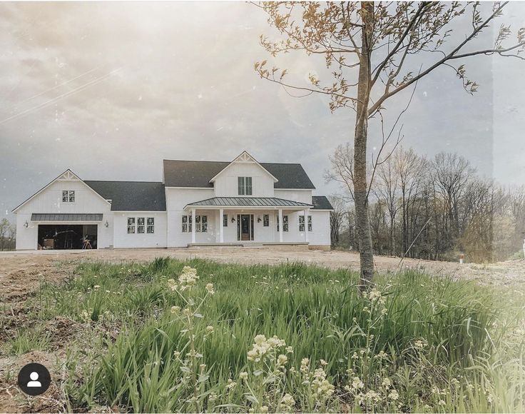 a large white house sitting on top of a lush green field next to a tree