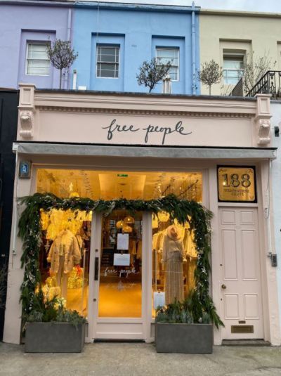 a store front with flowers and greenery on display