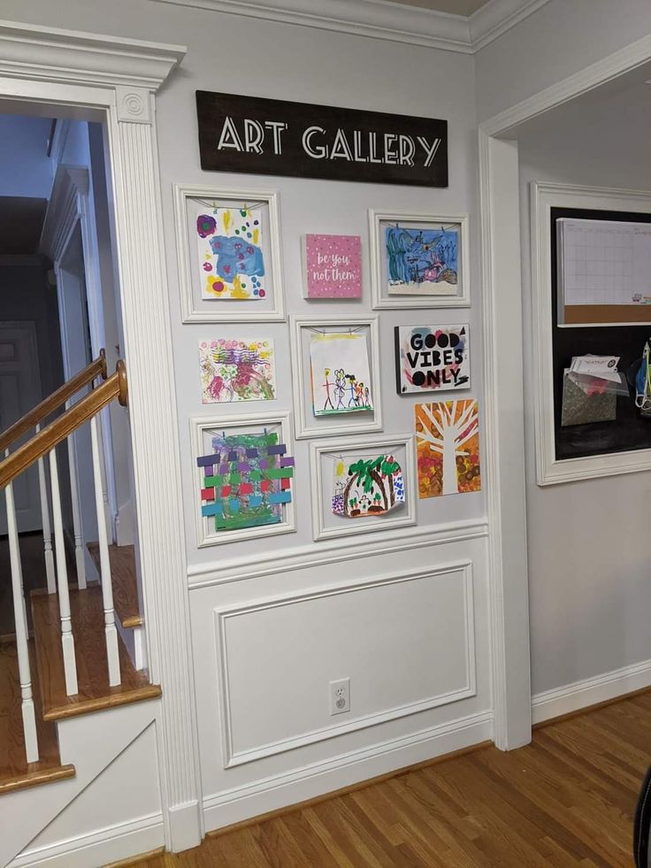 an art gallery is displayed on the wall next to a stair case with pictures and paintings