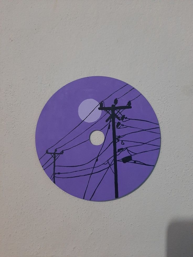 a purple disc with power lines and telephone poles in the background, on a white wall