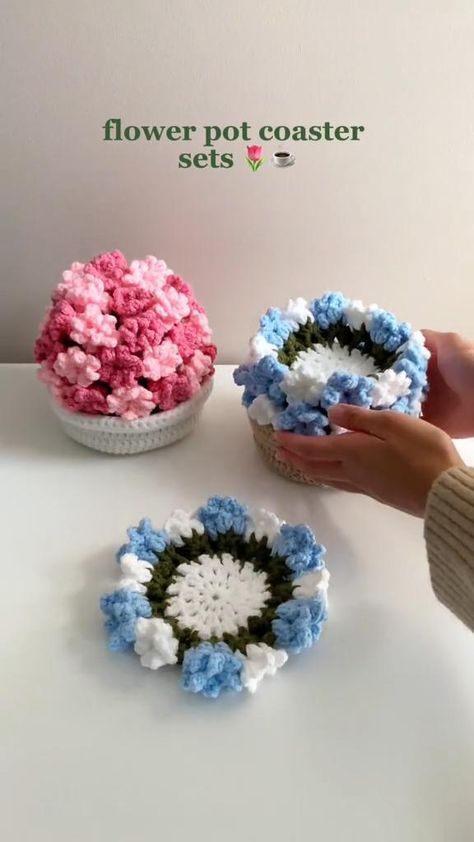 two crocheted flower pots sitting on top of a table next to each other