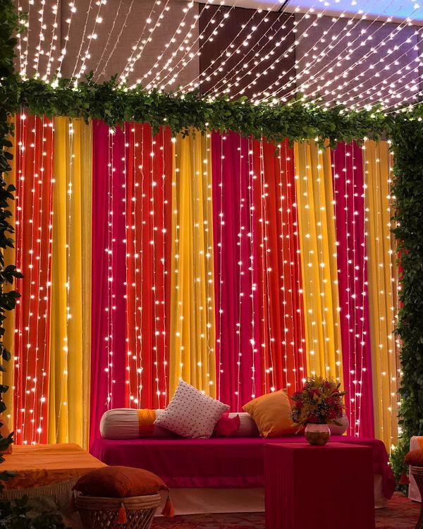 a living room filled with lots of furniture and lights hanging from the ceiling next to a red couch