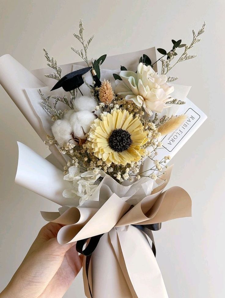 a person holding a bouquet of flowers in their left hand with the ribbon tied around it