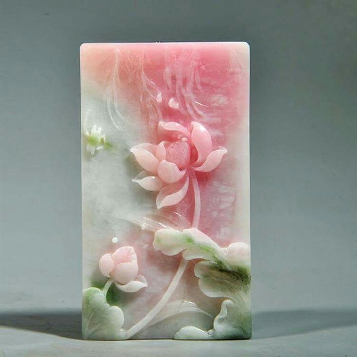 a pink and white square shaped soap with flowers on the front, sitting on a gray surface