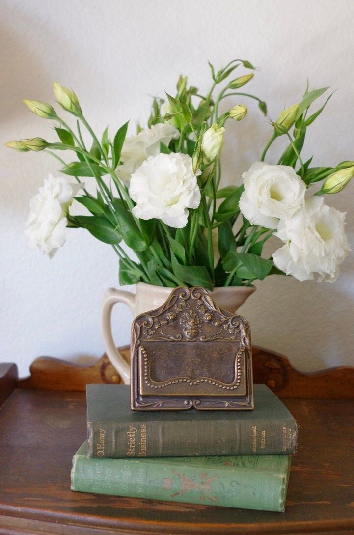 white flowers are in a vase on top of books