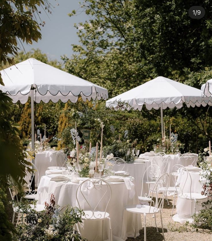 tables and chairs are set up under umbrellas for an outdoor wedding reception in the garden