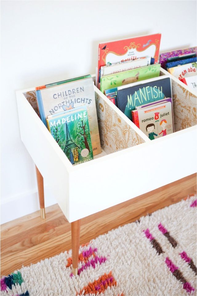 a book shelf with books in it on top of a rug next to a wall