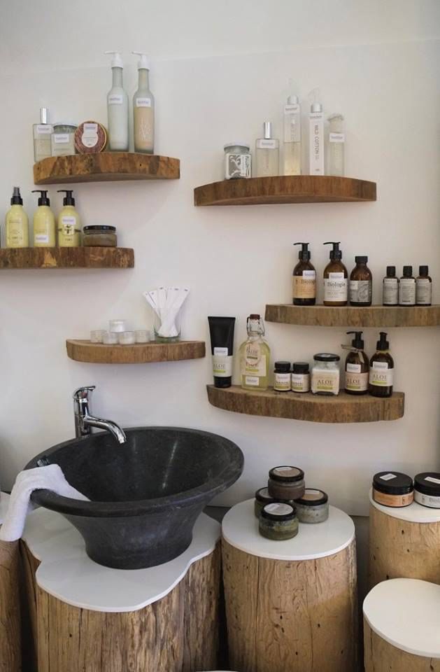 a bathroom sink sitting on top of a wooden counter next to shelves filled with bottles