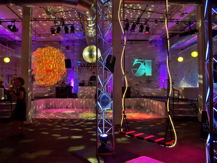 a room with purple lighting and decorations on the walls, as well as disco balls