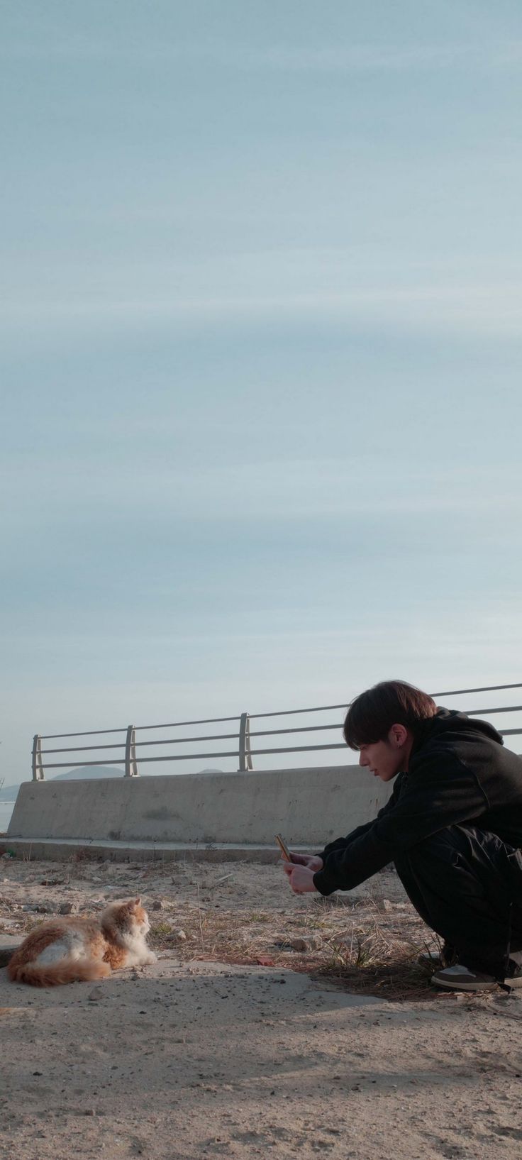 a man kneeling down next to a cat