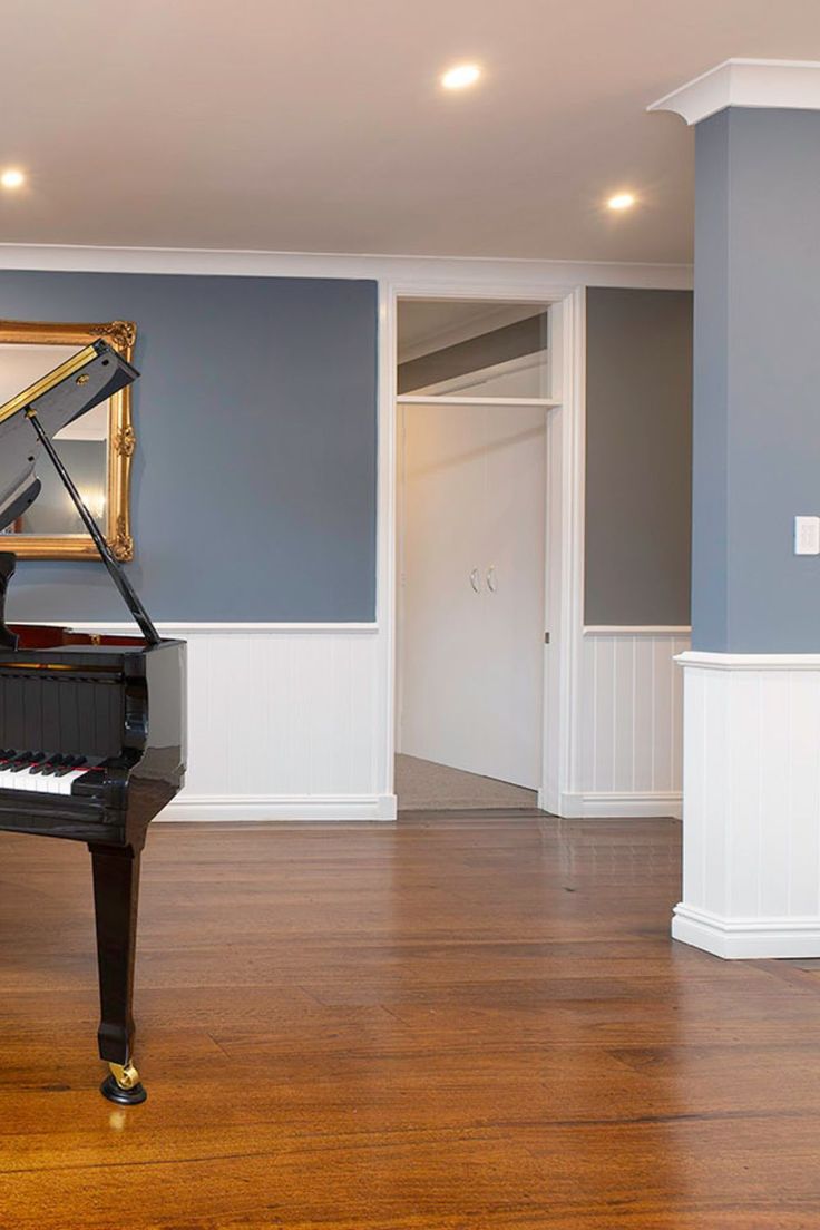 an empty room with a grand piano in the center and blue walls on either side