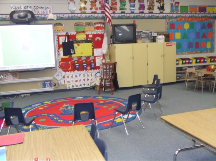 an empty classroom with desks, chairs and a flat screen tv on the wall