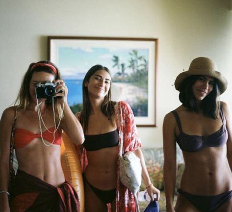 three women in bikinis are taking pictures