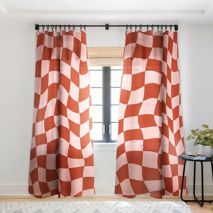 an orange and white checkered curtain hanging in front of a window