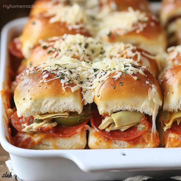 several sliders in a white casserole dish topped with cheese and tomato sauce