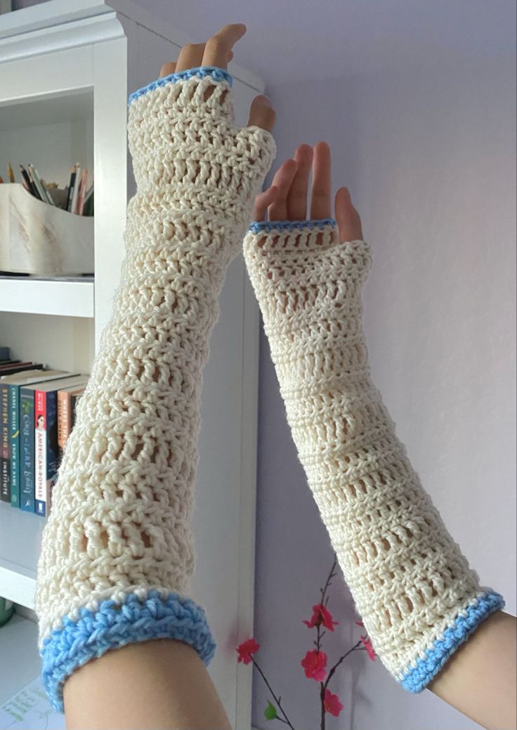 the arm warmers are crocheted with blue and white yarn, along with two fingers