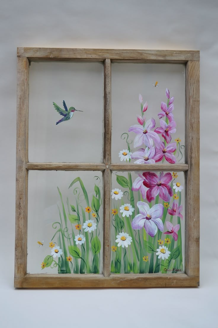 a window with flowers painted on it and a bird flying in the sky behind it