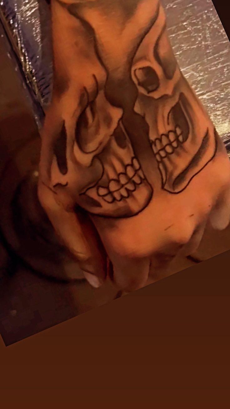 a hand with two skulls tattooed on it