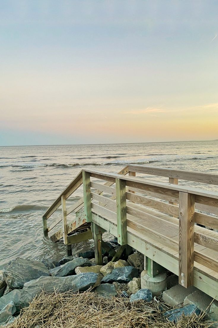 a wooden bridge over some rocks near the ocean