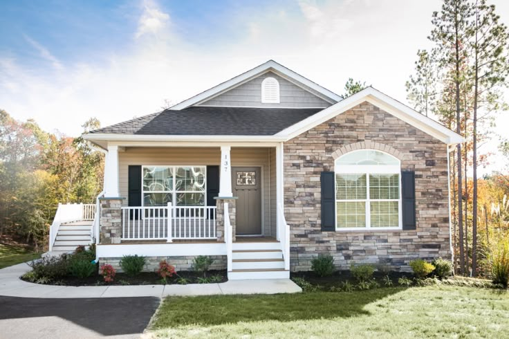 a small brick house with black shutters on the front porch and white stairs leading up to it