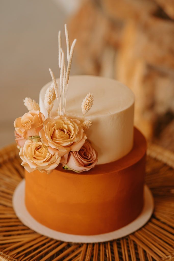 a close up of a cake with flowers on it sitting on a wicker table