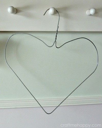 a heart hanging on a wall with three balls attached to the hooks and one string