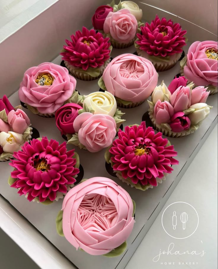 cupcakes decorated with pink and white flowers in a box