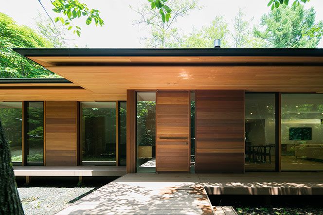 a modern house in the woods with wooden doors