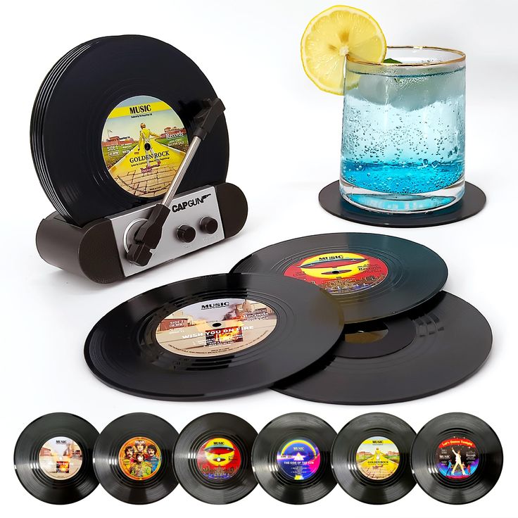 an old record player with six different records and a glass of water on the side