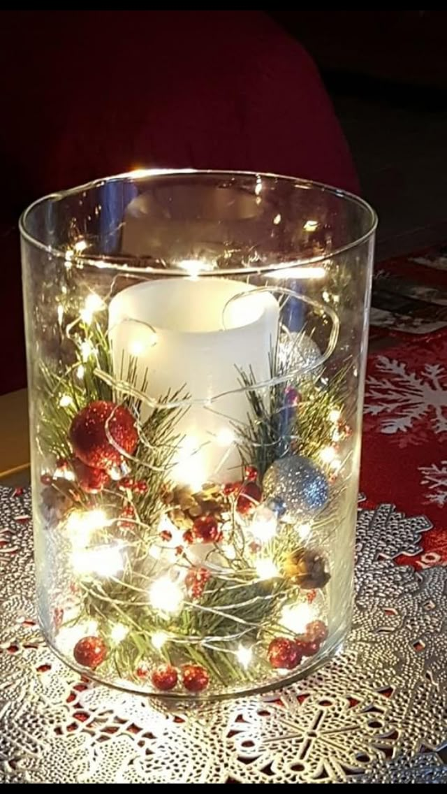 a lit candle in a glass container with christmas decorations