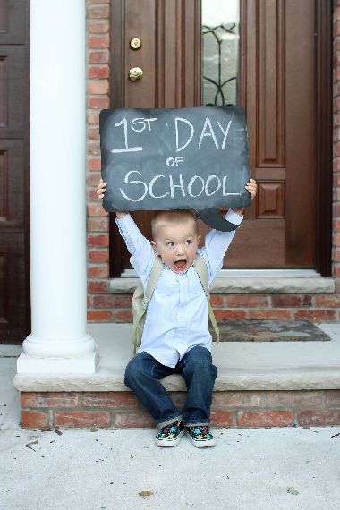 a young boy holding up a chalkboard that says 1st day of school