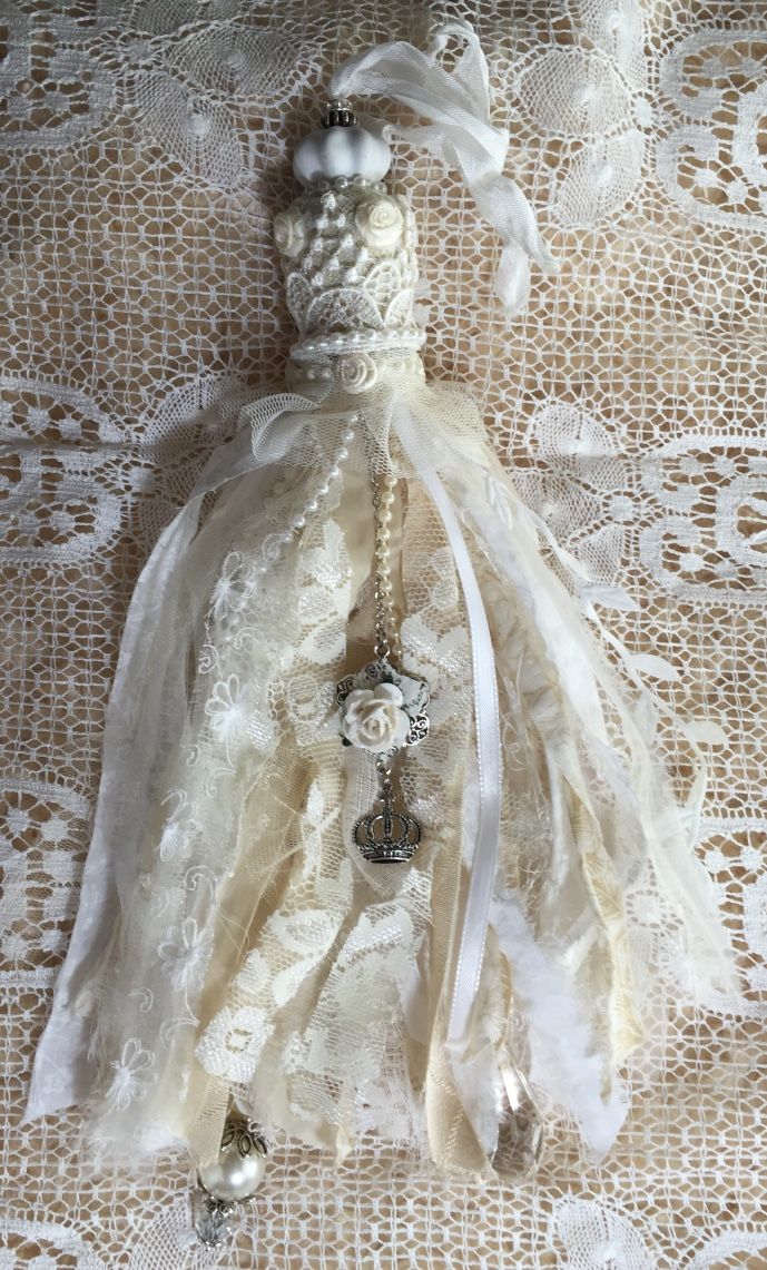 a white dress with pearls and lace on the bottom is laying on a tablecloth